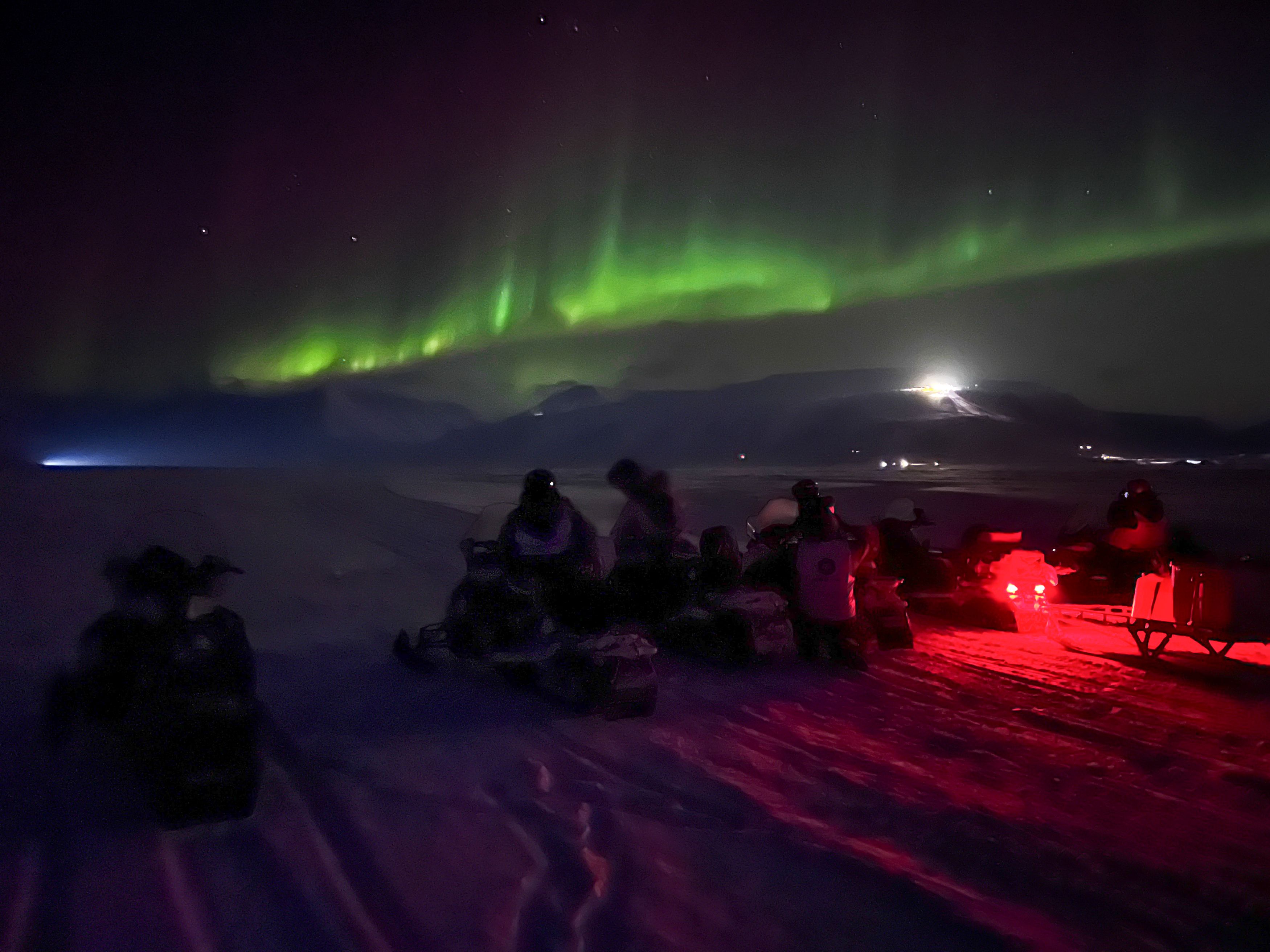 Northern lights under a frozen waterfall - by snowmobile - Snowfox